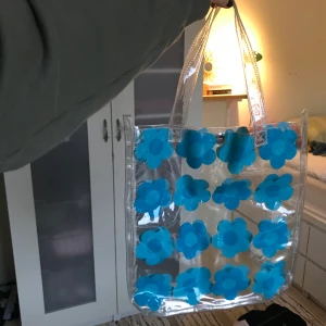 Genomskinlig väska - Supersöt väska i bra skick!! Den står mig varmt om hjärtat men tyvärr kommer den inte till användning så därför söker den nu ett nytt kärleksfullt hem🥺 själva väskan är 33x35 cm så ganska normalstor. frakt på 66 kr tillkommer