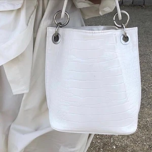 Väska Hvisk - Vit väska från Hvisk. Den är aldrig använd och har lappen kvar! Köpt för 845 kr för ett tag sedan men har inte kommit till användning. Kommer med ett kort och ett långt band som går att ta bort!! Köparen står för frakten.💛