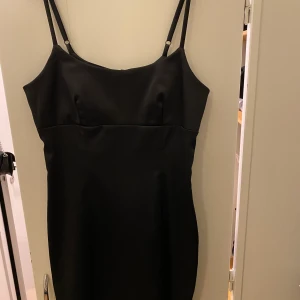 Coctailklänning svart i stl M  - Superfin Coctailklänning i stl M. Enkel modell med smala axelband. Köpt i NYC i butiken Forever 21. Materialet är glansigt och klänningen passar såväl till fest som högtider. Den är dessvärre för stor till mig och det är bättre att den kommer till användning. Tveka inte vid frågor angående modell och pris. Klänningen är i fint skick, i princip oanvänd.