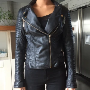  - Svart skinnjacka (konstläder) i fint skick förutom att dragkedjssmycket har gått av på ena ärmen (se bild 3) men det är inget som syns eller gör funktionen på dragkedjan sämre 