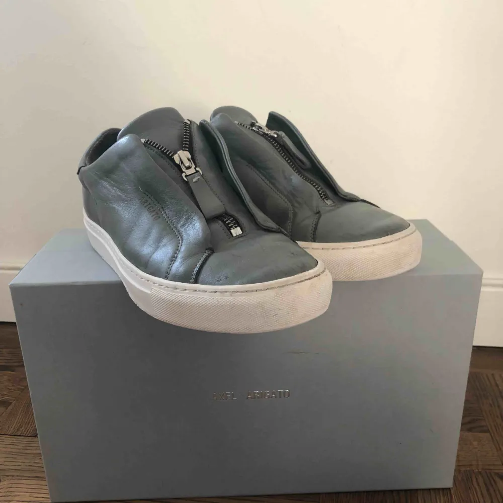 Ett par axel arigato skor i modell Clean 90 Zip sneaker. Använda en vår ungefär. Världens bekvämaste sko. Dragkedjan sitter fast och går inte att öppna men de sitter jättebra ändå och är super smidiga att sätta på.   Inköpspris: 1800kr. Skor.