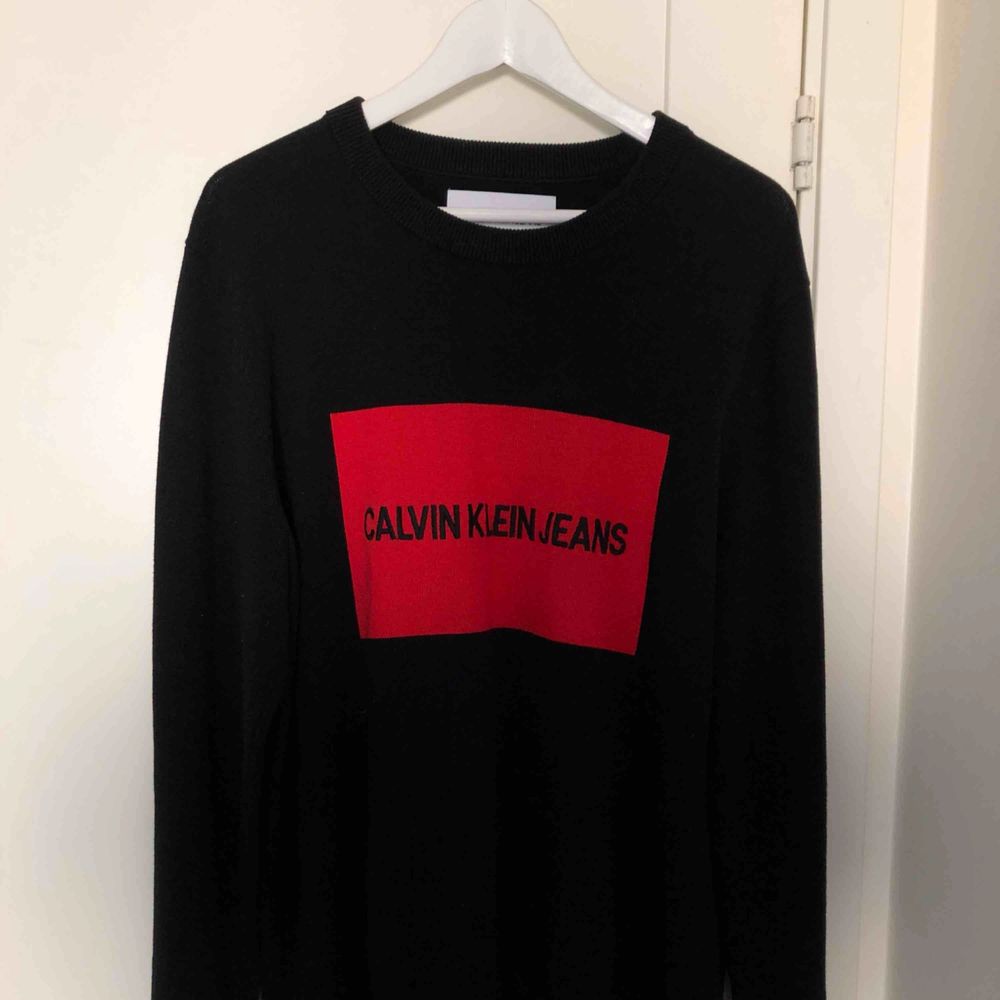 En svart stickad tröja ifrån Calvin Klein med röd logga  I bra skick, använd en gång  Inköpt för ca 800kr . Stickat.