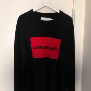 En svart stickad tröja ifrån Calvin Klein med röd logga  I bra skick, använd en gång  Inköpt för ca 800kr 