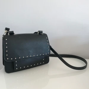 Svart handväska - En svart handväska i den där perfekta mellanstorleken från Pull&Bear🙌 Avtagbart och reglerbart axelband, magnetförslutning och tre olika fack där du får plats med alla dina nödvändigheter💫 Frakt 44kr.