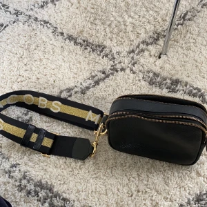 Marc Jacobs väska - Väska från other stories med band från Marc Jacobs. Knappt använd, lappen sitter kvar. Rymlig och bra med två fack. Väskan kostade ca 1500kr tillsammans. Följer med en dustbag i vitt från other stories. 