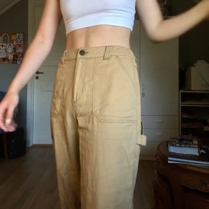 Beiga byxor  - Ett par beiga byxor från asos i ”snickarmodell”. De är i storlek 38. Nypriset var 400kr