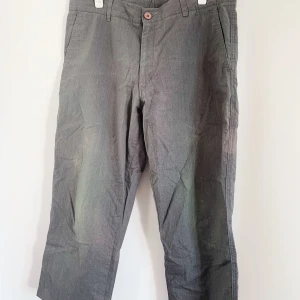 Grå kostymbyxor  - Grå kostymbyxor i en kortare modell. Snygga fickor på baksidan, och knapp på fram. Köpta secondhand. Relativt lågmidjade.