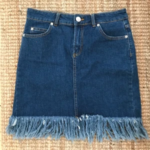 Jeanskjol River Island - Oanvänd jeanskjol med fin detalj längst ner från River Island. Storlek 12 (EUR 40). Pris ex. frakt 🌸