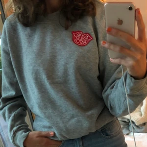 Bakbok grå sweatshirt - Grå sweatshirt från bikbok som med mening (alltså köpt så) har lite hack i sig tex vid nacken och ger en vintage känsla. Röd detaljerad patch på bröstkorgen också. Väldigt mjukt material inuti, super mysig! Kan frakta för 25kr och mötas upp i Stockholm🥰