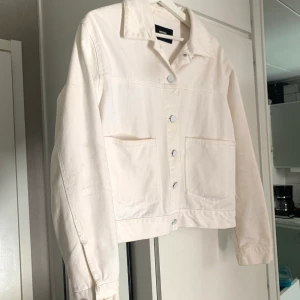 Jeansjacka  - Vit jeansjacka från Bikbok i strl L. Den har två stora fickor på sidorna och modellen är lite kortare. Använd några gånger bara. 150kr + 79kr frakt.