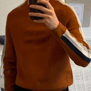 Jules tröja - Slim fit tröja storlek medium. Rostbrun i färg med grå, vit, blå linjer längs armarna. Använd 3ggr. 