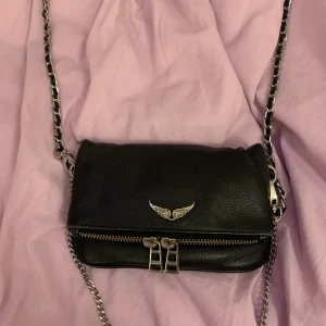 Zadig Voltaire väska - En svart Zadig Voltaire väska som har två olika band. Väskan är i helt okej skick men den har blivit lite sliten på på vissa ställen. Väskan är köpt för ca 2000. Väskan kostar 1100 kr!