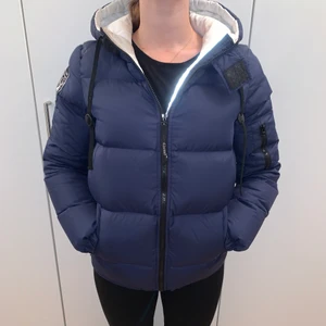 db jacka i marinblått strl M - Marinblå jacka ifrån db sweden storlek M. Har i vanliga fall storlek S i kläder. Varm, tjock och mysig, får plats med tjockare tröja under. Snodd i nederkant man kan reglera hur man vill att den ska sitta åt. Innerficka med blixtlås. Lite oversize. 2000kr nypris.