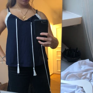 Blått linne med vita detaljer - Supergulligt mörkblått linne, med vita snören och vita spetsdetaljer. Köpt för 150 kr, säljer för 40 kr.