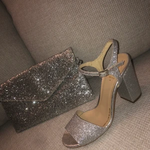 Klackar och kuvertväska - Säljer mina super fina och glittriga Milano klackar i jätte bra skick. Har köpt dessa klackar utomlands för 100 euro. Väskan får du med gratis. Har använt dessa klackar och väskan endast en gång på min bal, därför säljer jag nu de då de inte kommer till användning. Kan mötas i Stockholm.