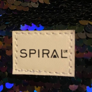 SPIRAL väska  - Jag säljer dena SPIRAL paljett väska som aldrig har använts. Det är en magväska men den funkar även som en kort axelväska, men om man vill kan man justera längden. Säljer denna för 15kr + frakt som ligger på 35kr. Alltså  50kr totalt.