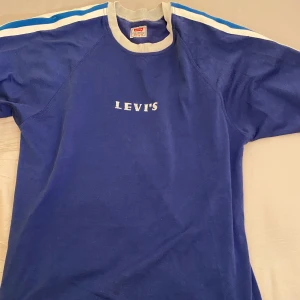 Blå Levis t-shirt - en cool tshirt från levis jag köpt på second hand för länge sedan, men helt enkelt bara inte kommit till använding. det står att den är XL men jag som har M tycker inte att den verkar så stor. frakt tillkommer!