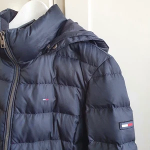 Blå dunjacka från Tommy Hilfiger - Säljer min väldigt snygga dunjacka från Tommy Hilfiger i storlek M. Väldigt sparsamt använd en vinter. Finns så man kan sätta på en päls på huvan om man vill. Passar till allt och är väldigt stilren. Köpte den för 3000kr men säljer den för 500kr och vid snabbt köp frifrakt!💕💕skriv privat om du har några frågor