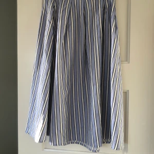 Fin sommarkjol - En fin sommarkjol, ner till mitten av vader/ smalben, randig med vitt, ljusblått och svart. Frakt ingår ej i pris