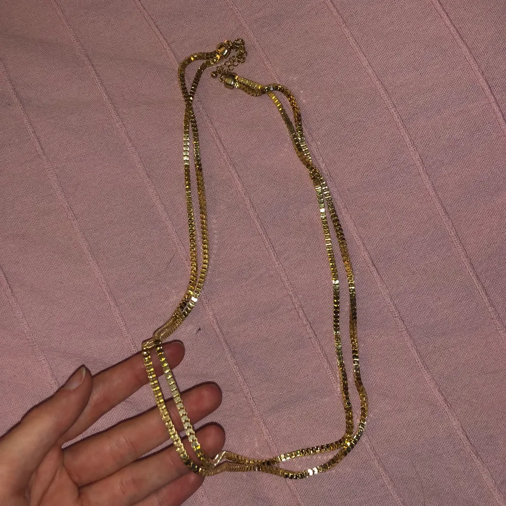 Halsband som inte är använt, ganska lång och i guld. Accessoarer.