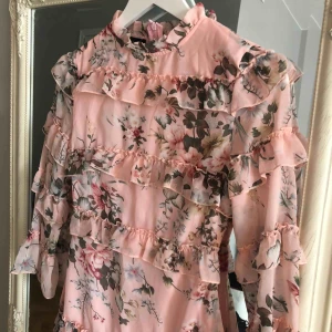  - As fin ljusrosa klänning med blommor och volanger! Superfin till sommar och midsommar! Oanvänd, lapp sitter kvar. 