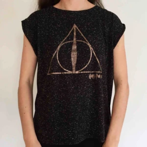 T-shirt  - T-shirt med Harry Potter inspiration. Svartmelerad med tryck i guld. Ganska liten i storleken (jag har vanligtvis S) Skriv till mig vid intresse och om du har några frågor eller vill se fler bilder☀️ Fraktkostnad tillkommer! 