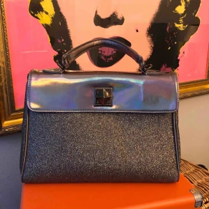  - Material Girl metallic glittrig väska med rosa innefoder désignât av Madonna.  Bud börjar på 180 SEK Fint skick, lite sliten på handtag. 