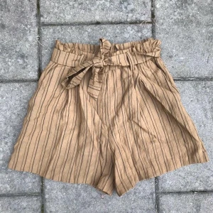 Paperbagshorts - Säljer dessa randiga shorts med ett band i midjan som går att knyta som man vill! Inköpta förra sommaren men de är aldrig använda ❤