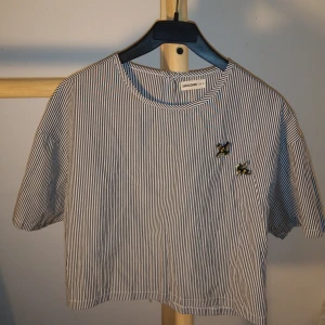 Unik topp  - Unik, oanvänd topp från 24colours! Köpt i Berlin. Fina bin sydda på framsidan och knappar på baksidan. Kort i midjan och fin knyten i midjan och använd med jeans. 