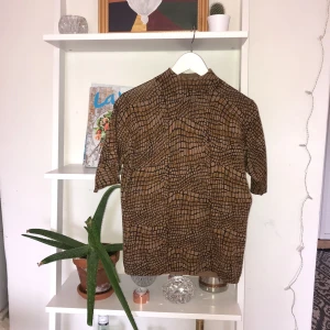  - Brunmönstrad polo med ett litet hål i halsen som lätt går att laga! Syns inte heller när man sätter på sig den