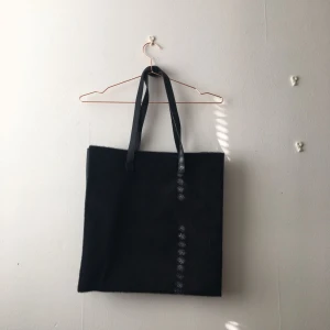  - Toteväska med fuskpäls, lite större än A4, har tre fack i varav ett med dragkedja, rymlig och smidig