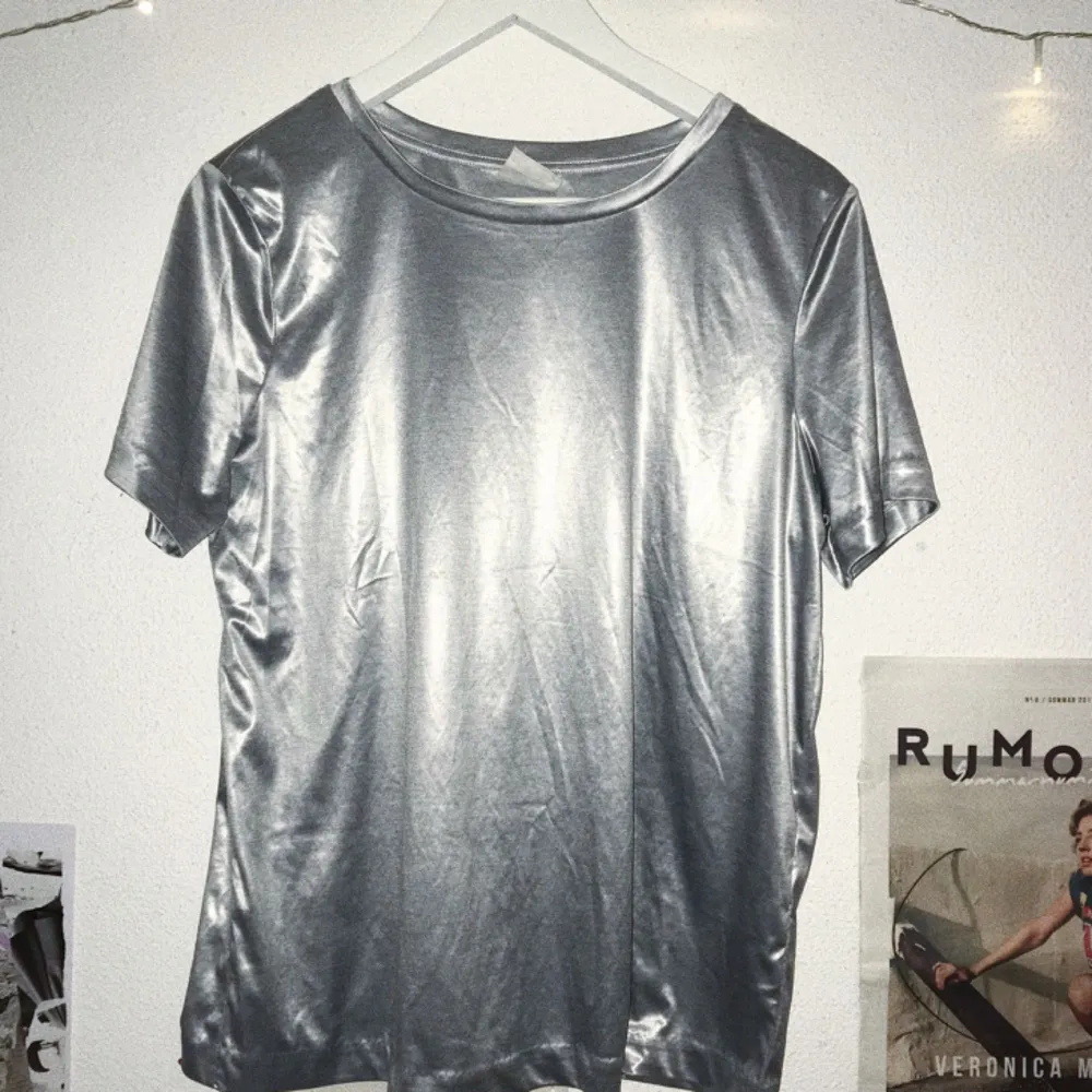 Silvrig t-shirt från H&M STUDIO. Såld för kvinnor men fungerar unisex.  Om kund bor utanför Lund/Malmö får den stå för pris av frakt <33. T-shirts.