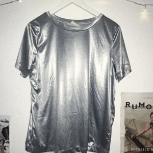  - Silvrig t-shirt från H&M STUDIO. Såld för kvinnor men fungerar unisex.  Om kund bor utanför Lund/Malmö får den stå för pris av frakt <33