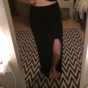  - Svart, skön kjol med slits från Gina tricot. Härligt silkes-aktigt tyg, med en innerkjol. Lång kjol med resår i midjan. Aldrig använd! Köparen betalar frakt!