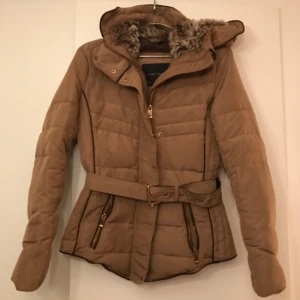  - Varm vinterjacka från Zara i beige med guldiga & bruna detaljer. Luvan vadderad med fakepäls. 