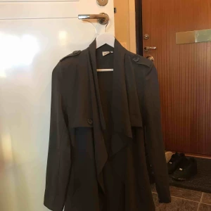  - Grå superfin jacka i nyskick, tunna axelvaddar och knapp dekorer samt knytning. 