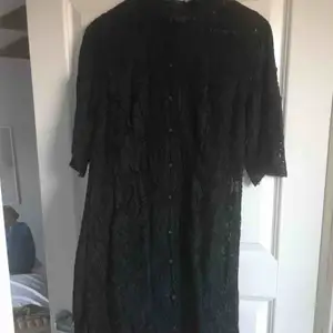 Fin spetsklänning i svart med klädda knappar och spetskrage