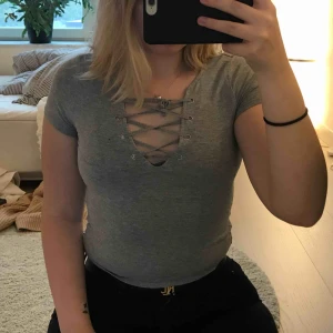  - Grå t shirt med snörning. Inga imperfektioner. Frakt på 20kr. Skicka meddelande vid frågor eller mer bilder💗
