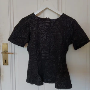  - Snygg peplumtopp med jaquardmönster    från STOCKH OLM. Mönstringen är i mjukt sammetsliknande material. Stretchigt tyg! 70% viskos, 28% polyamid, 2% elastan