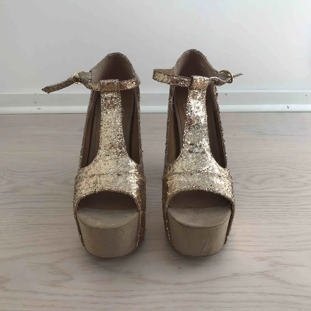 Guldglittriga högklackade skor i nyskick. De är använda endast två gånger. 13 cm klackhöjd. Köparen står för fraktkostnad enligt postens portotabell.. Skor.