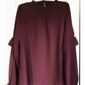  - En superfin vinröd tröja som är storlek M men även S!  Använd knsppt, två ggr max så den är som ny! Bra skick! Den är lite genomskinlig och har lite volanger i ärmarna, riktigt fin!