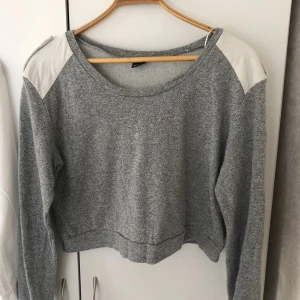  - Grå snygg sweatshirt från Gina tricot i storlek L. Mocka imitation på axlarna med knapp. Använd men i fint skick. Frakt tillkommer. 