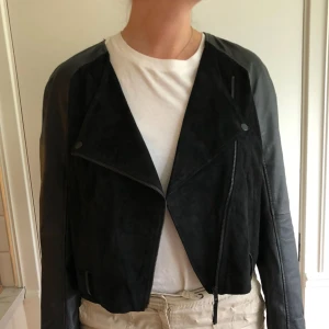  - En svart jacka från Monki i skinn- och mockaimitation. Sparsamt använd. 