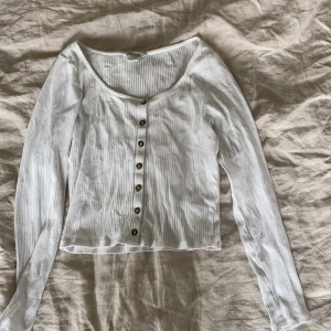 Vit ribbad tröja med knappar - Säljer denna fina ribbade tröjan men knappar från Monki. Säljes då den inte kommer till användning 