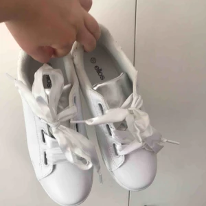  - Vita sneakers med silkesband som skosnöre. Från Ellos egna märke. Passar mig som har 38. Aldrig använda. 150 + frakt. Kan mötas upp i tranåsområdet eller i sthlm.