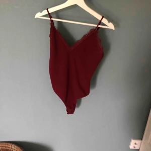  - Vinröd body med spets kant runt brösten 