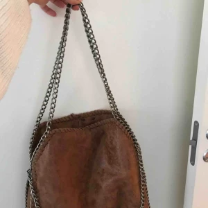  - Superfin väska med kedja och mocca material. Köpt i Spanien. Supersnygg med tre kedjor vilket gör att man kan välja mellan att ha den längre upp eller lite längre ner.  Köpare står för frakt!