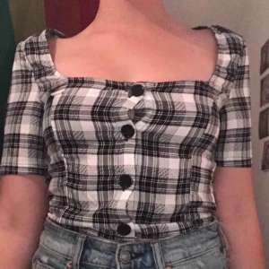  - Svart vit rutig blusaktig, med knappar som går att öppna. Priset kan diskuteras, (aldrig använd förutom på bilden)