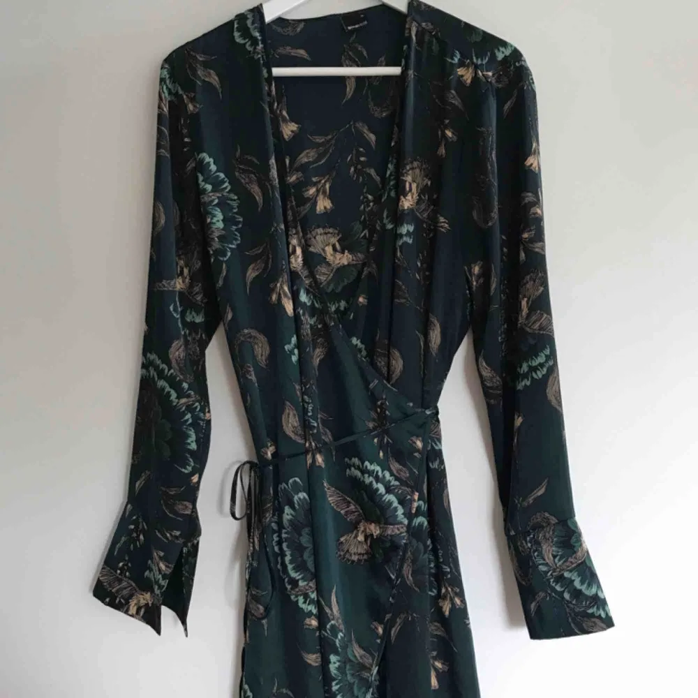 Kimono-klänning i glansigt tunt material. V-ringad med omlottknytning i midjan, lätt utställda ärmar, slutar under knät. Kan användas som klänning eller morgonrock. Frakt tillkommer på 50 kr <33. Klänningar.