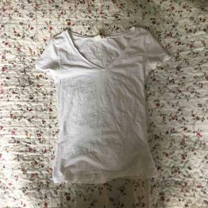 Väldigt tight v-ringad t-shirt i vitt från H&M. Litet hål vid ena ärmen. Lite genomskinlig. Frakt tillkommer.